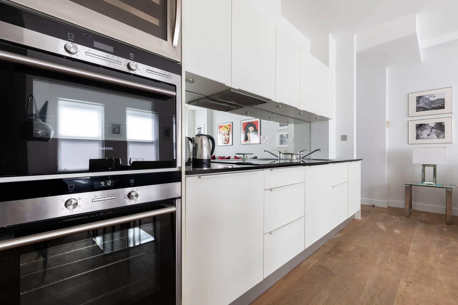 A modern kitchen with white cabinets, built-in appliances, and a long countertop.