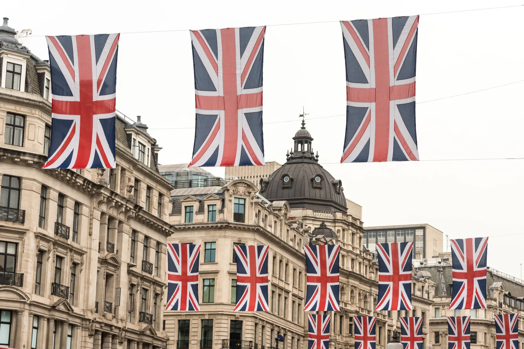Union Jack flags hang above a city street lined with ornate stone buildings.