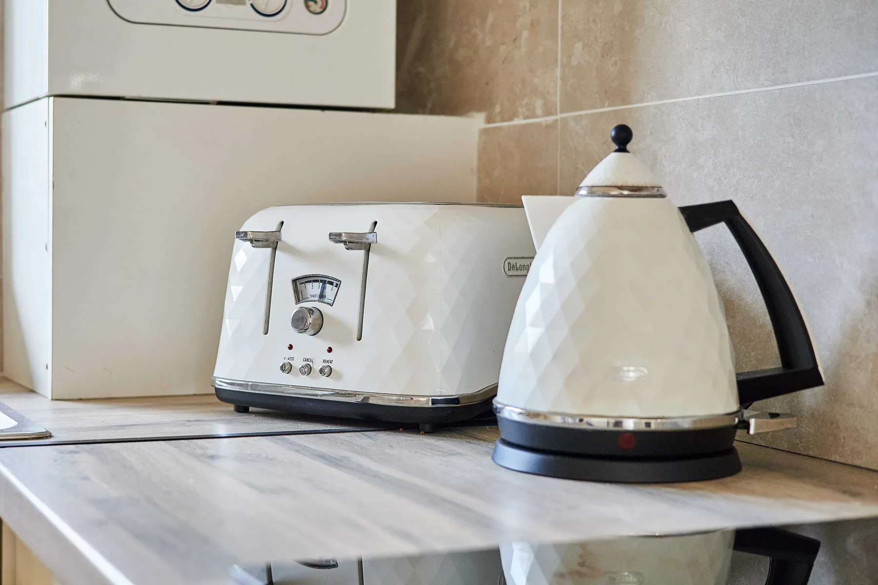 Una encimera de cocina tiene una tostadora blanca y un hervidor eléctrico.