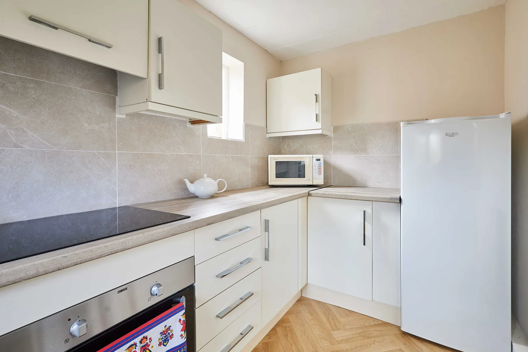 Una cocina compacta con gabinetes blancos, un microondas y un refrigerador.