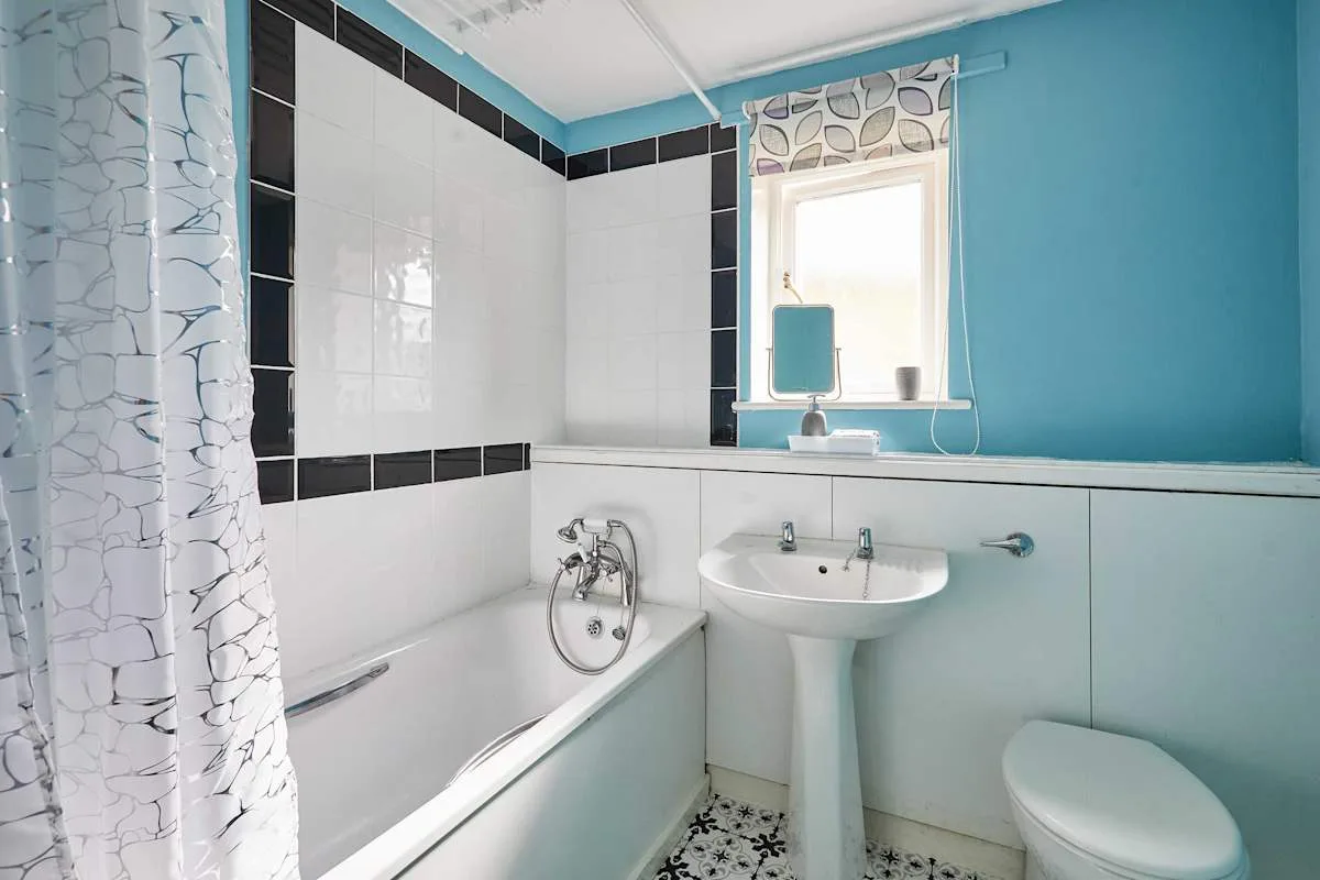 Un baño con bañera, lavabo con pedestal e inodoro.
