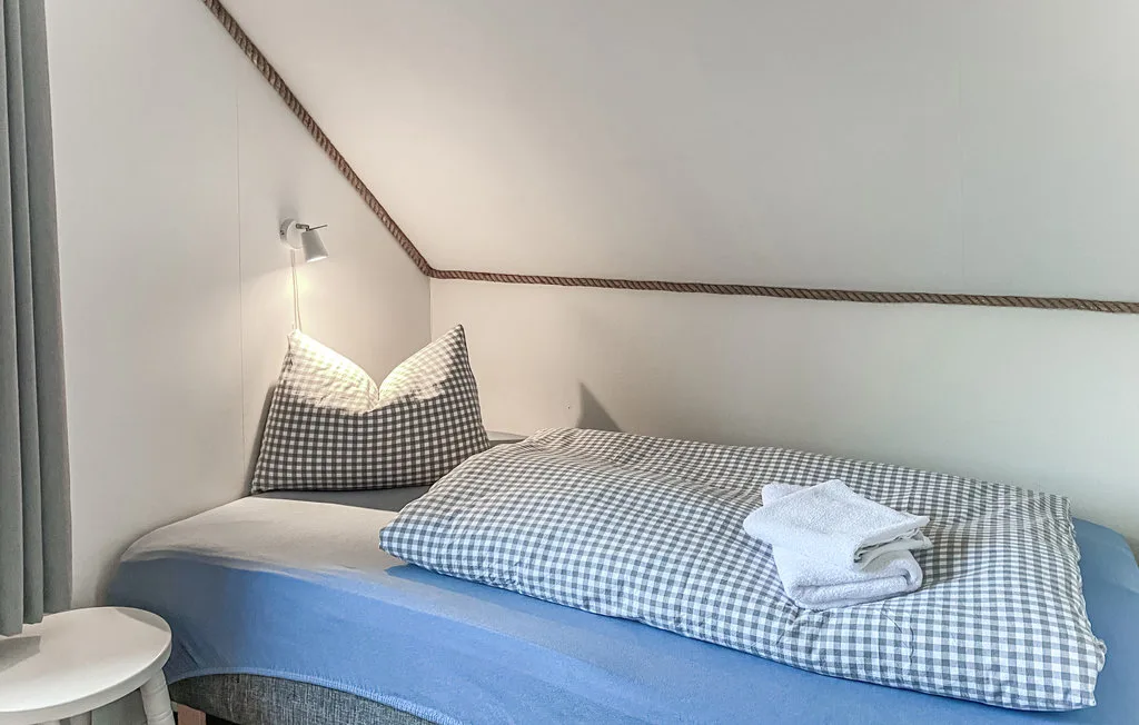 Una cama con ropa de cuadros azules y blancos y toallas dobladas en un dormitorio.