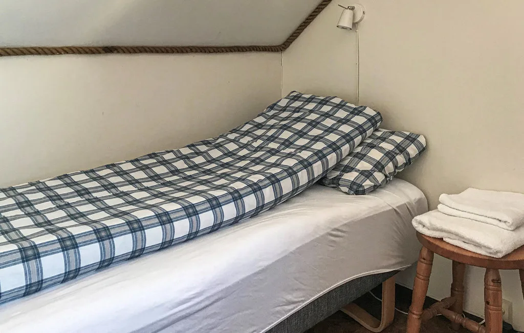 Una pequeña zona para dormir con una cama cubierta de ropa de cama a cuadros azules.