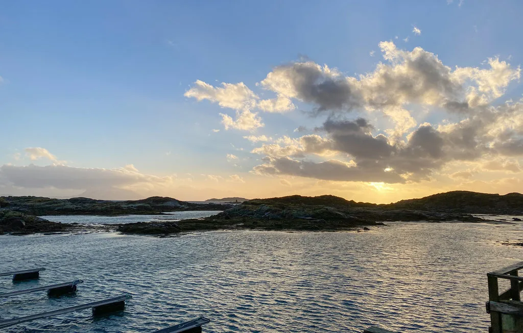 Un paisaje costero al atardecer, con islas rocosas frente a aguas tranquilas.