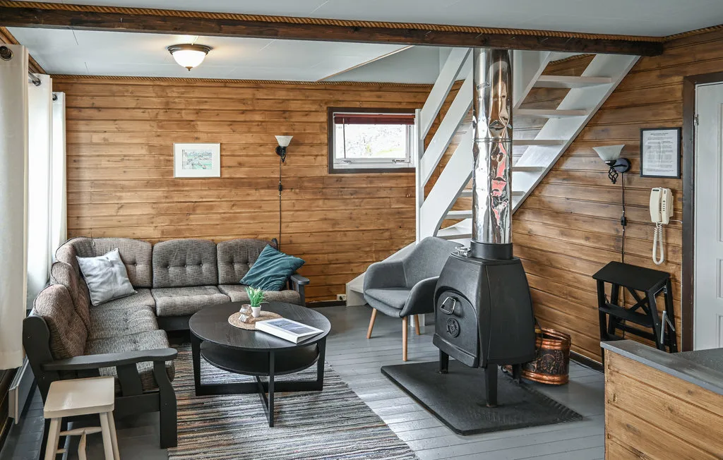 A wood-paneled living room with seating, a coffee table, and a freestanding stove.