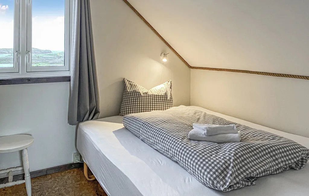 Un dormitorio con una cama vestida con ropa de cuadros bajo un techo inclinado.