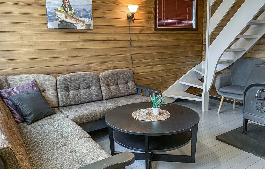 Una sala con paredes de madera tiene asientos seccionales y una mesa de centro redonda.