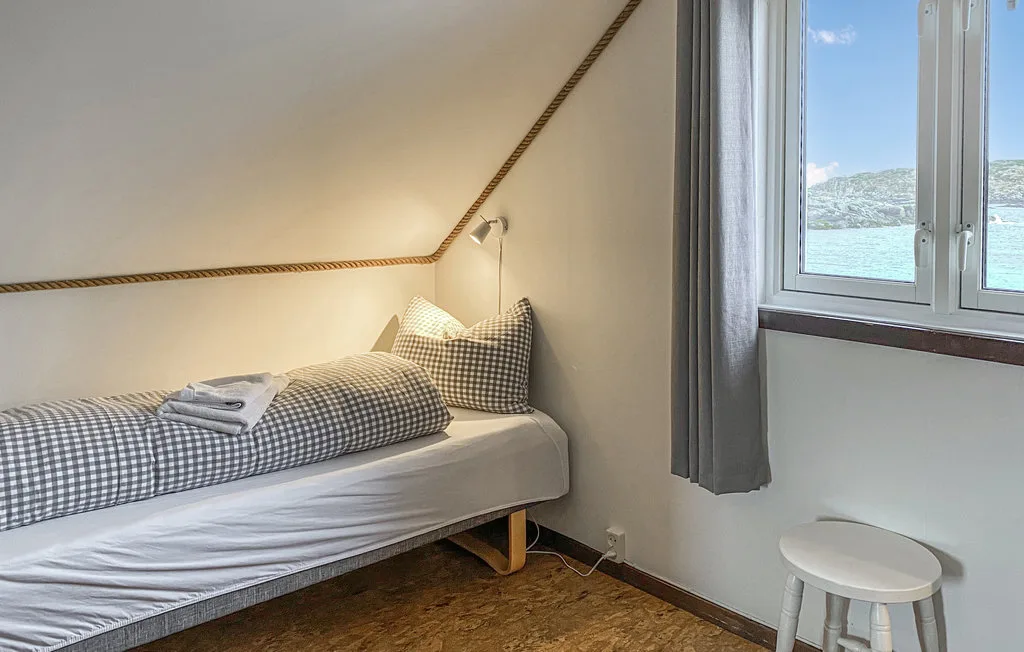 Un dormitorio pequeño tiene una cama junto a una ventana con vistas al agua.
