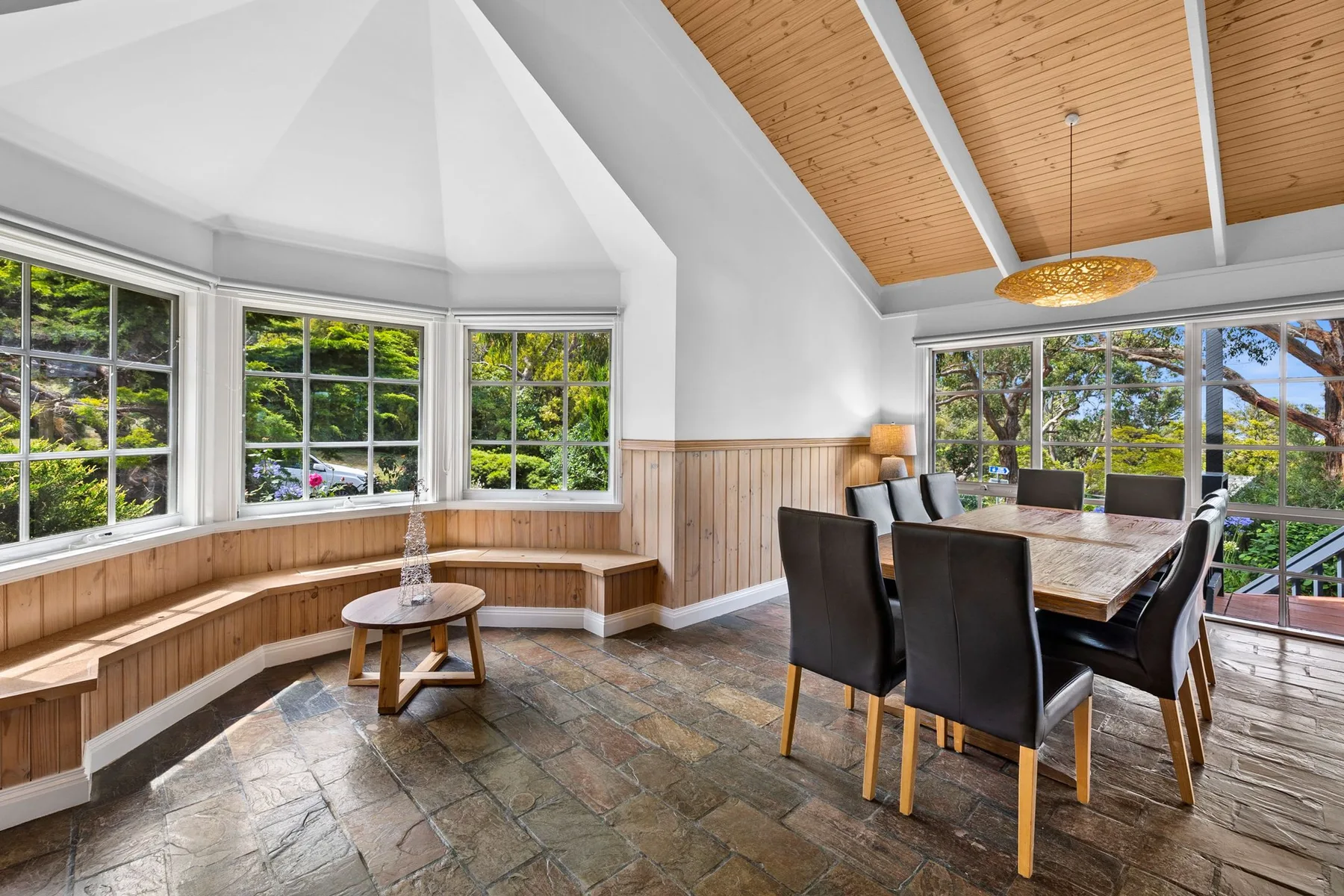 Un comedor luminoso con una mesa de madera y ventanas con vistas a la vegetación.