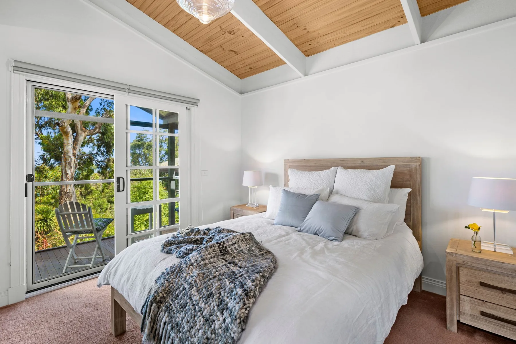 Un dormitorio luminoso con una cama bajo un techo revestido de madera.