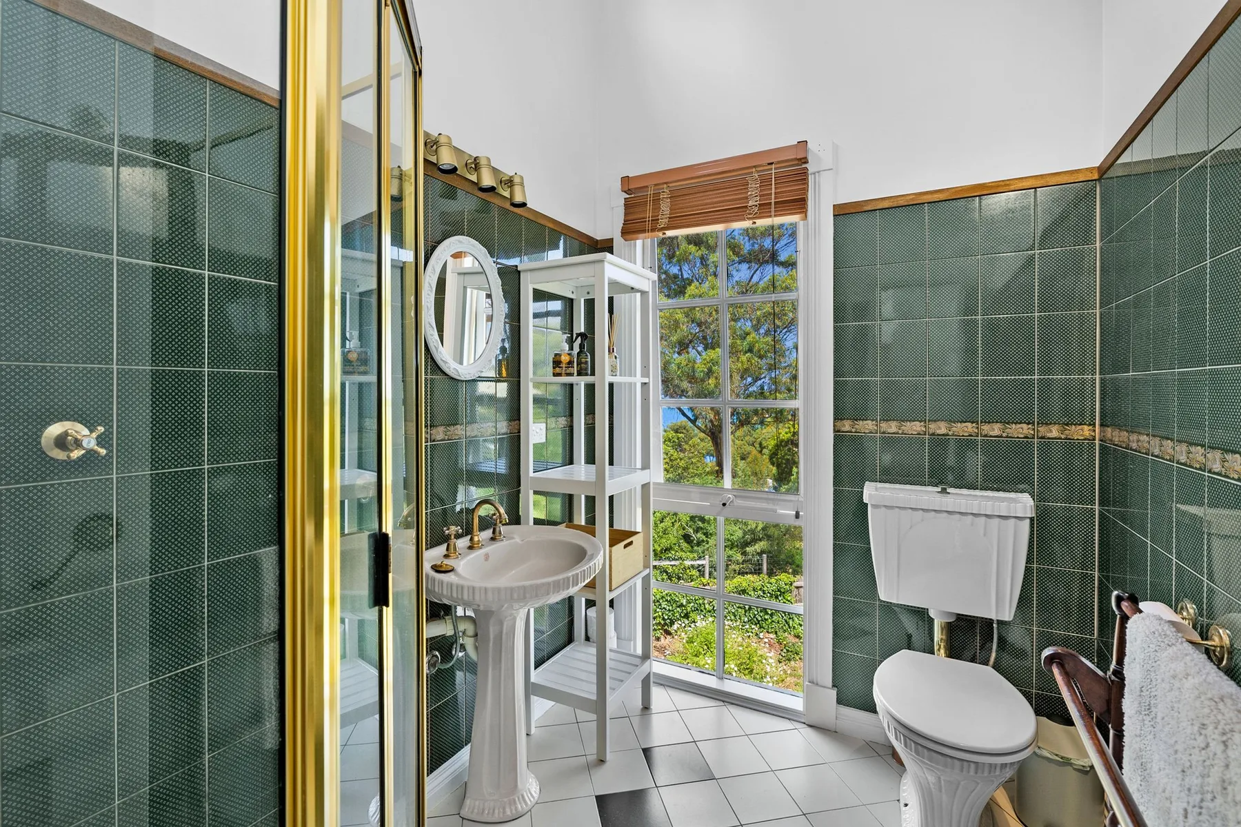 Un baño alicatado con lavabo, inodoro y una ventana amplia.