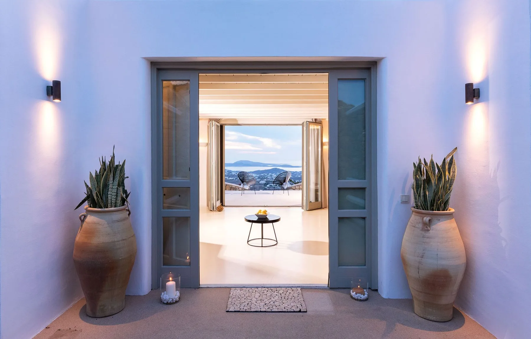 Una puerta abierta da a una habitación luminosa con vistas a las montañas.