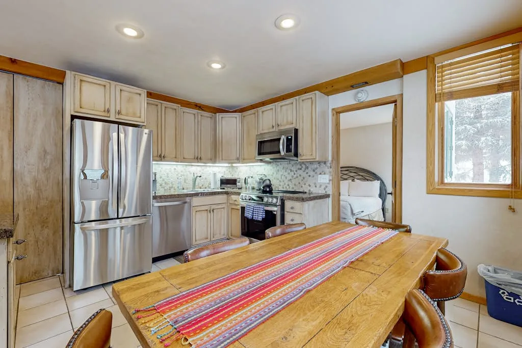 Una cocina y comedor con una mesa de madera y un camino de mesa colorido.