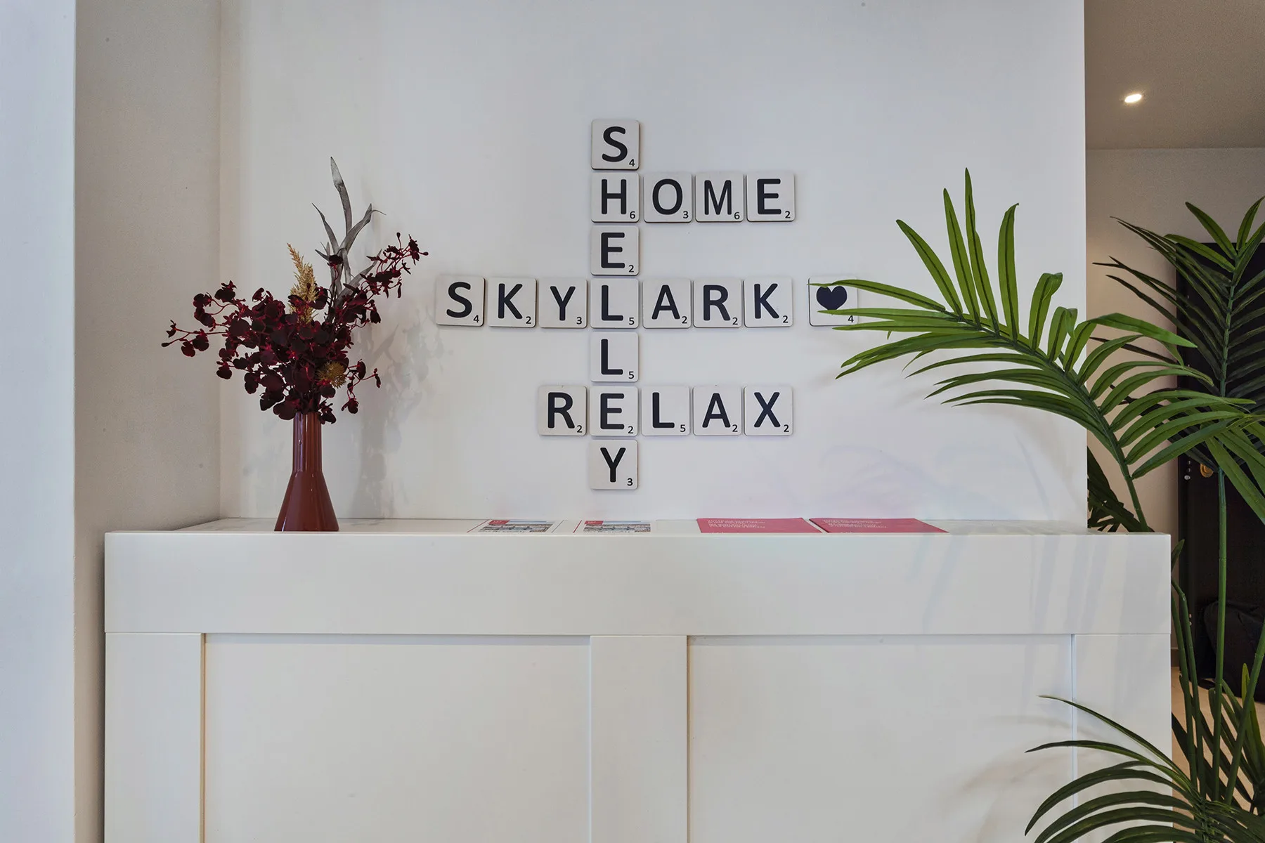 A reception counter displays letter tiles spelling a welcome-themed message, with plants on either side.