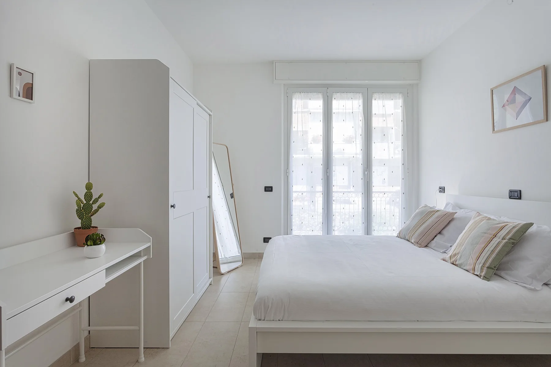 A bright bedroom with a bed and tall windows.