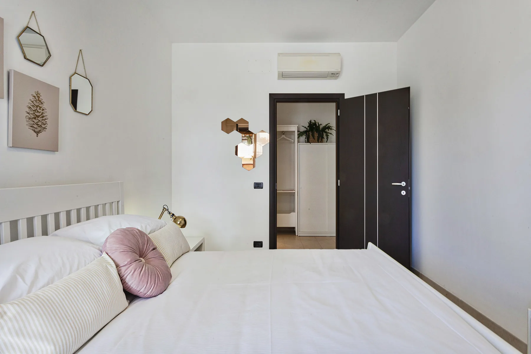A bright bedroom with a neatly made bed and an open doorway.