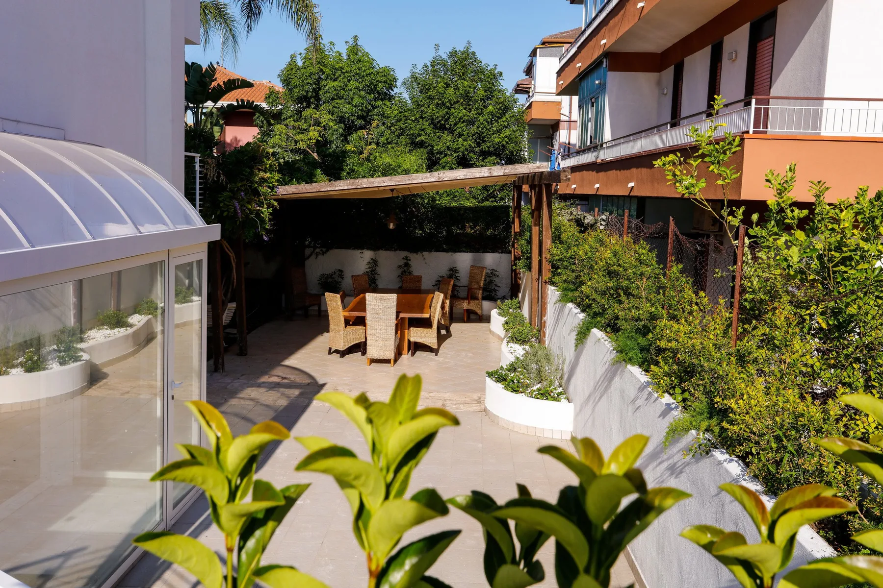 Un patio comedor al aire libre con una mesa y asientos bajo una zona cubierta.