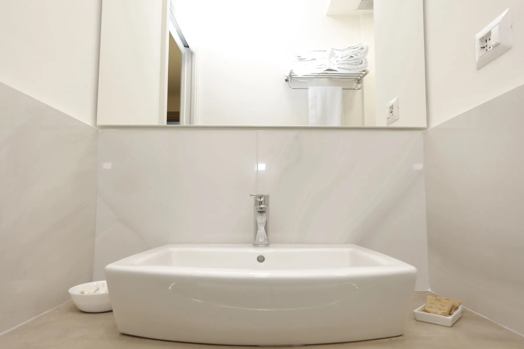 Un lavabo de baño con una amplia cuenca debajo de un gran espejo.