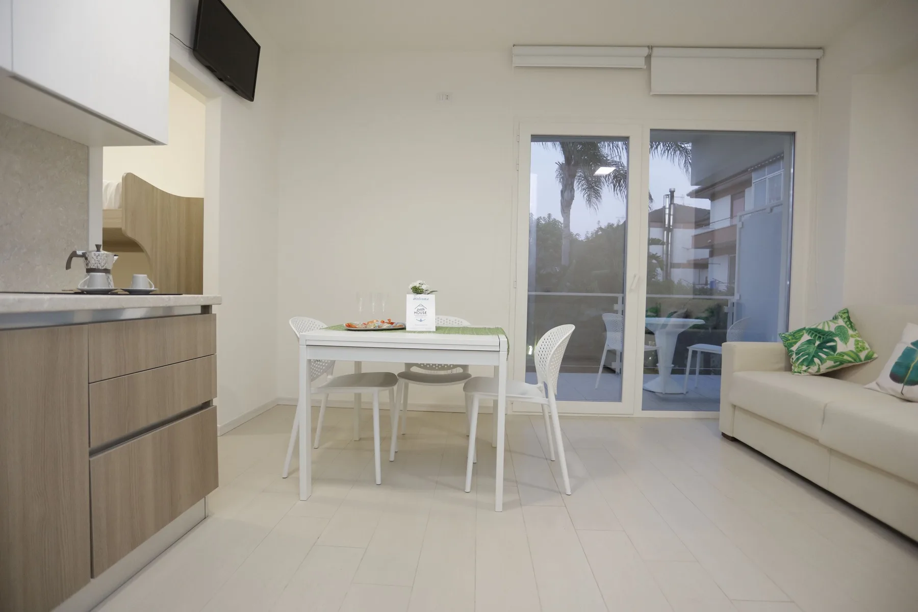 Una luminosa sala de estar y comedor con una mesa junto a puertas corredizas de vidrio.