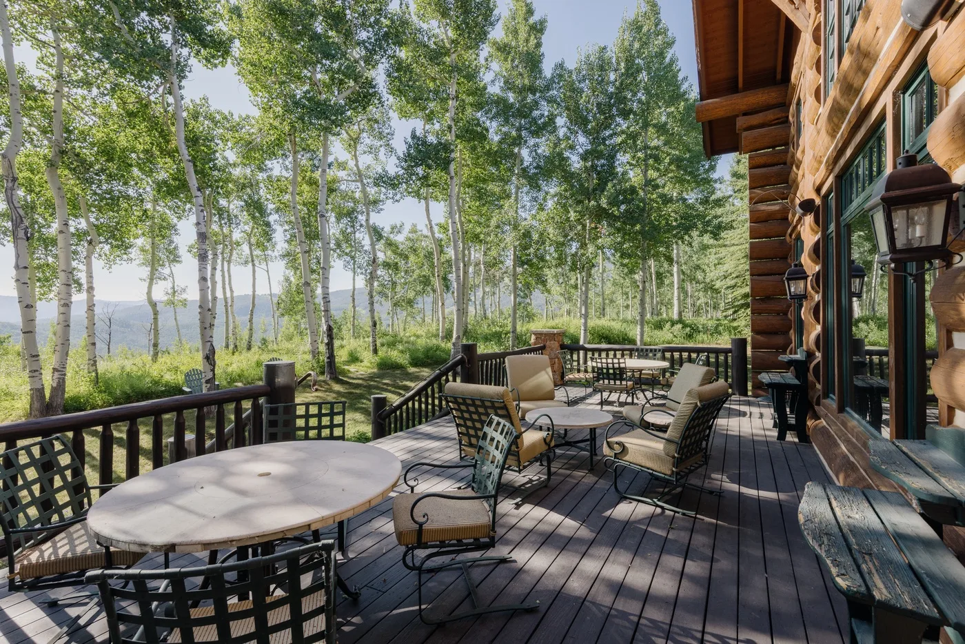 Una terraza de madera con asientos al aire libre da a un paisaje arbolado.