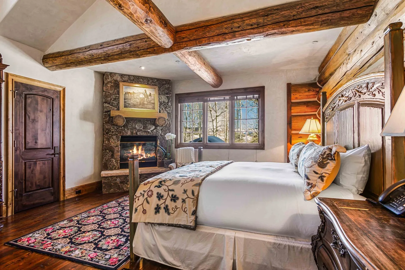 Un dormitorio con una cama grande, una chimenea y vigas de madera expuestas.