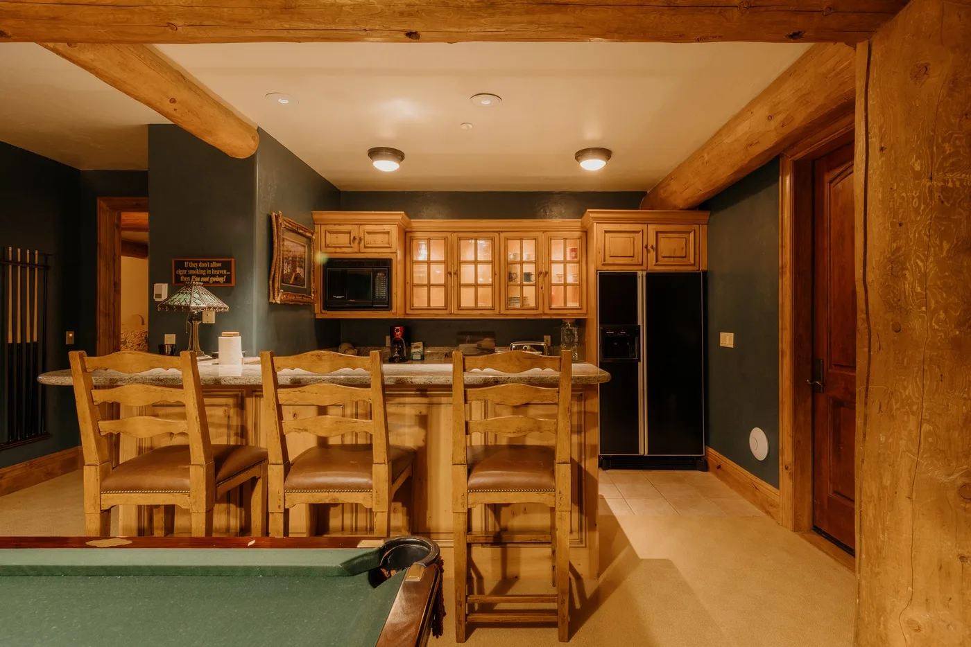 Cocina y comedor con gabinetes de madera, una barra y asientos.