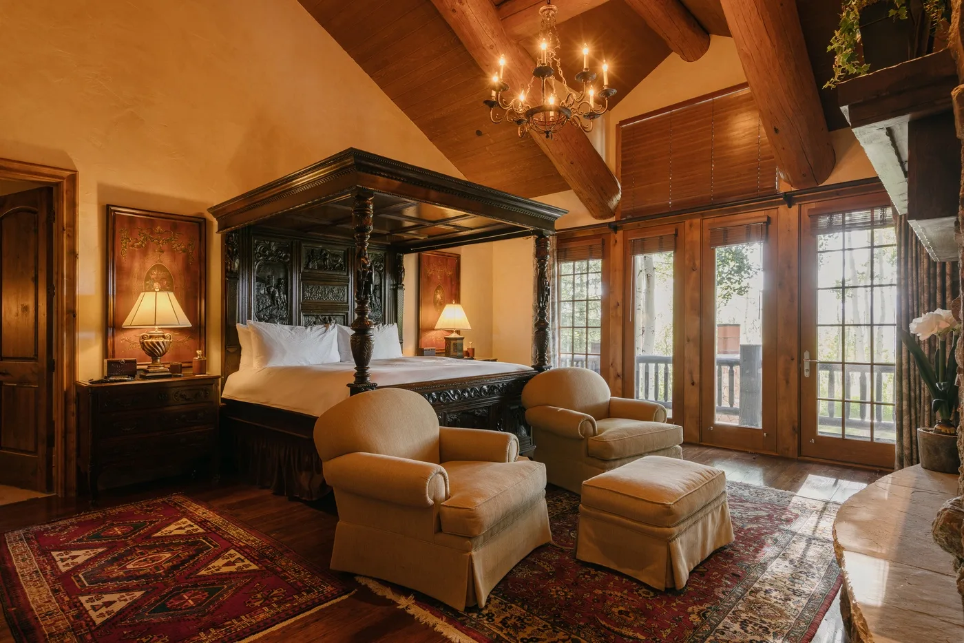 Dormitorio con cama con dosel, sillones y ventanas altas.