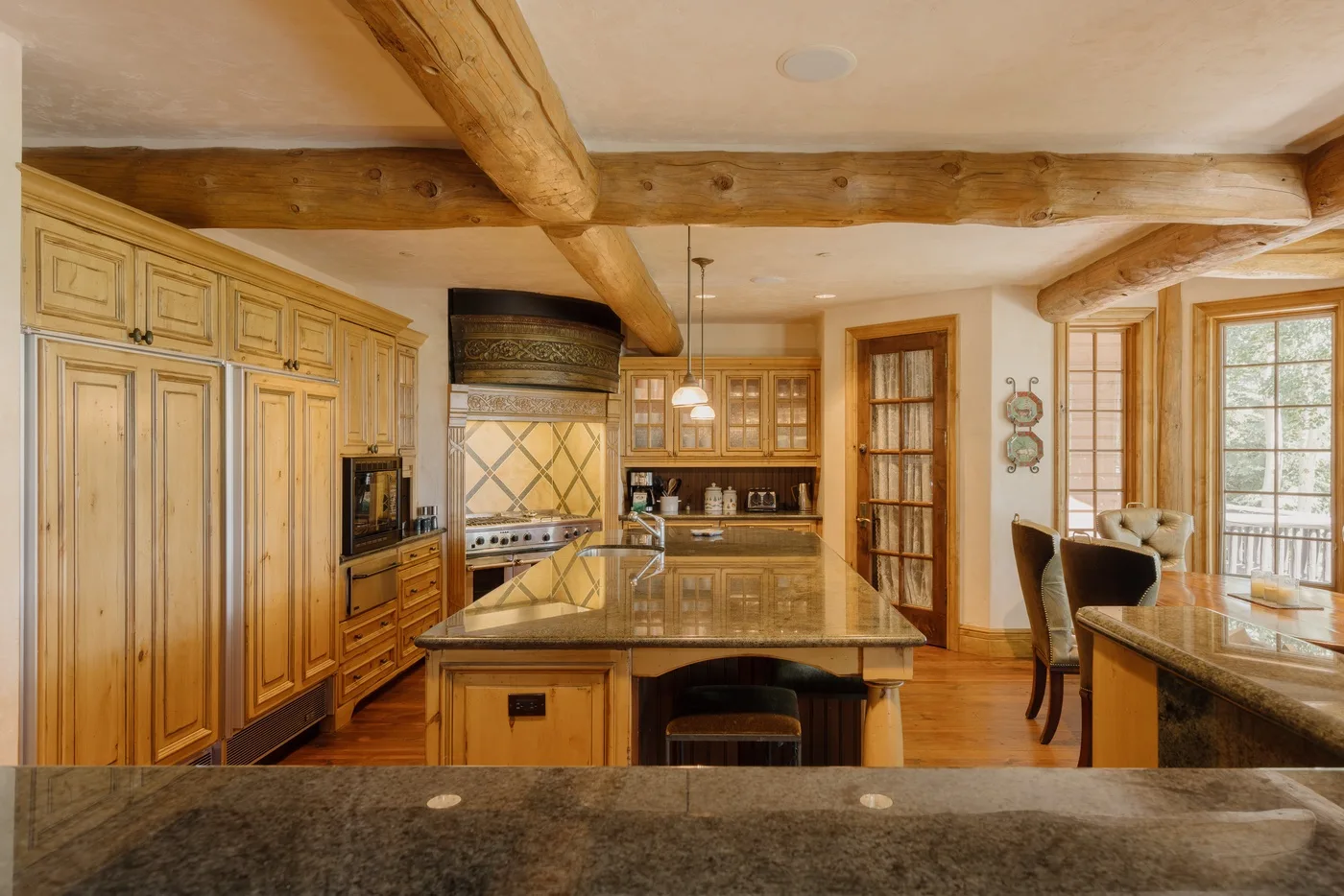 Una cocina amplia con gabinetes de madera, encimeras de piedra y vigas expuestas.