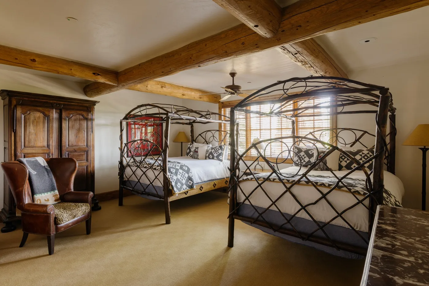Un dormitorio con dos camas de estructura metálica bajo vigas de madera expuestas.