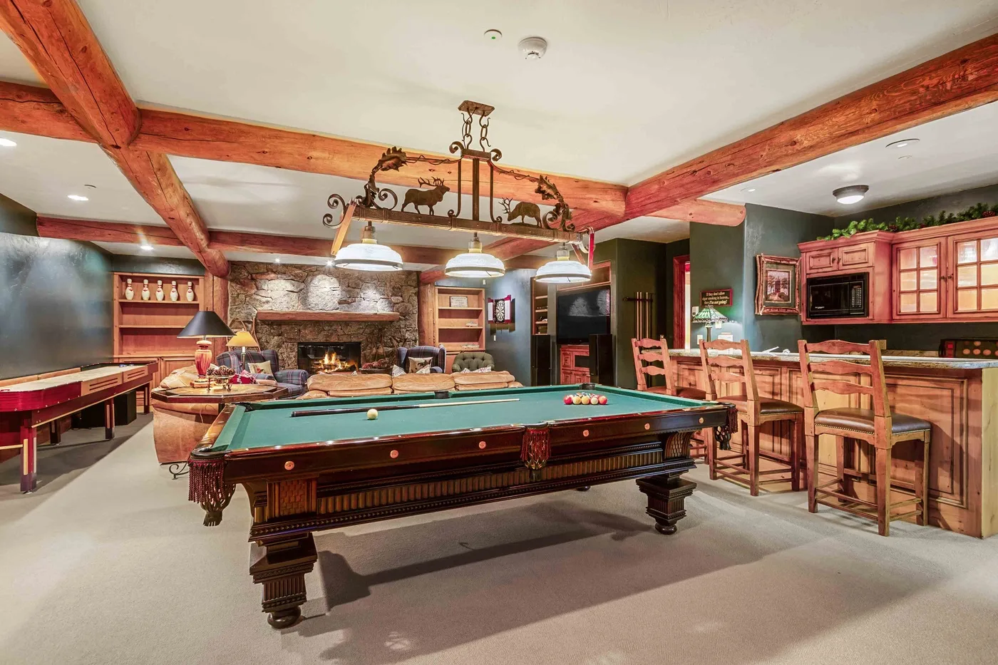 Una sala de juegos con mesa de billar, asientos y chimenea.