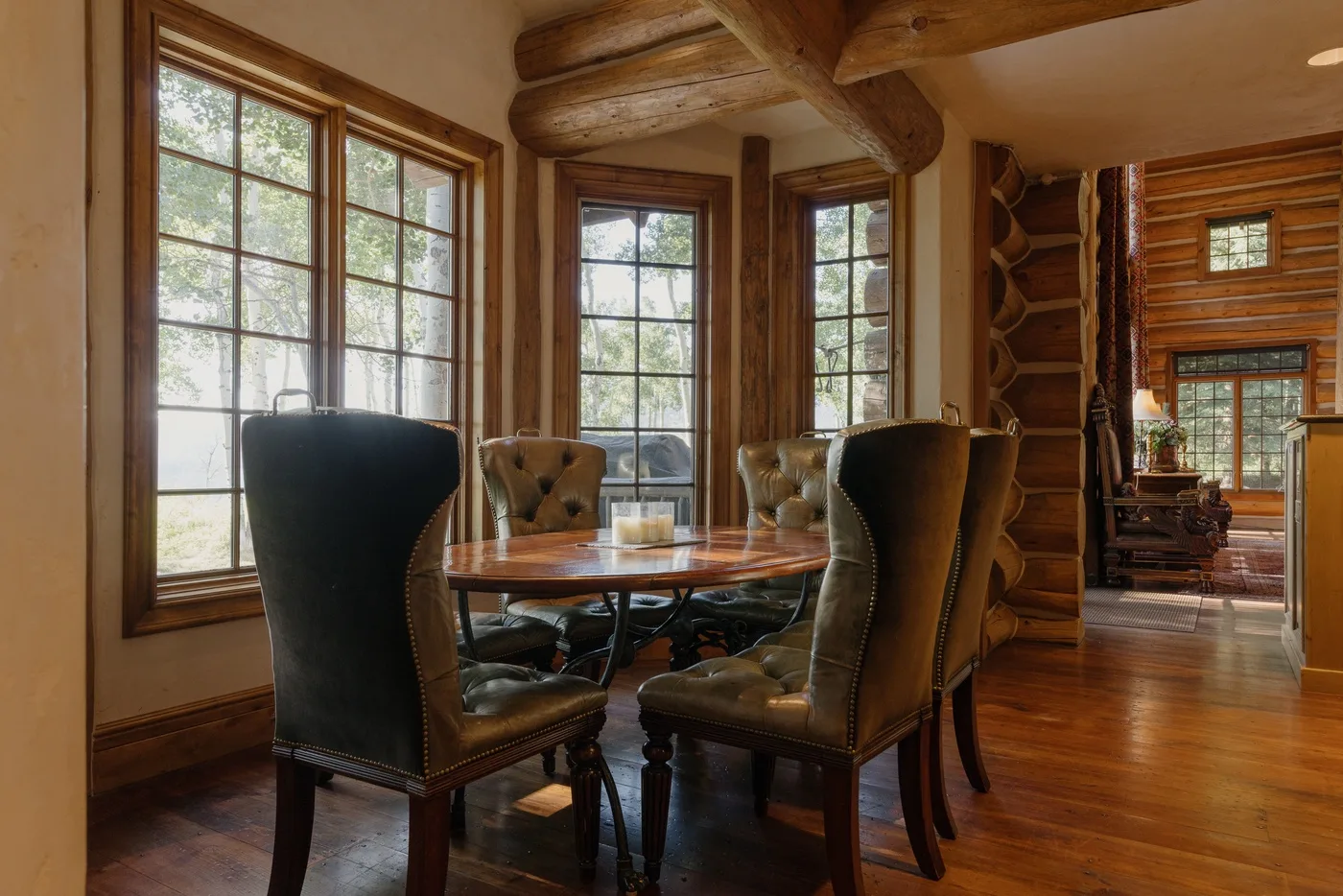 Comedor revestido de madera con una mesa y asientos junto a grandes ventanas.