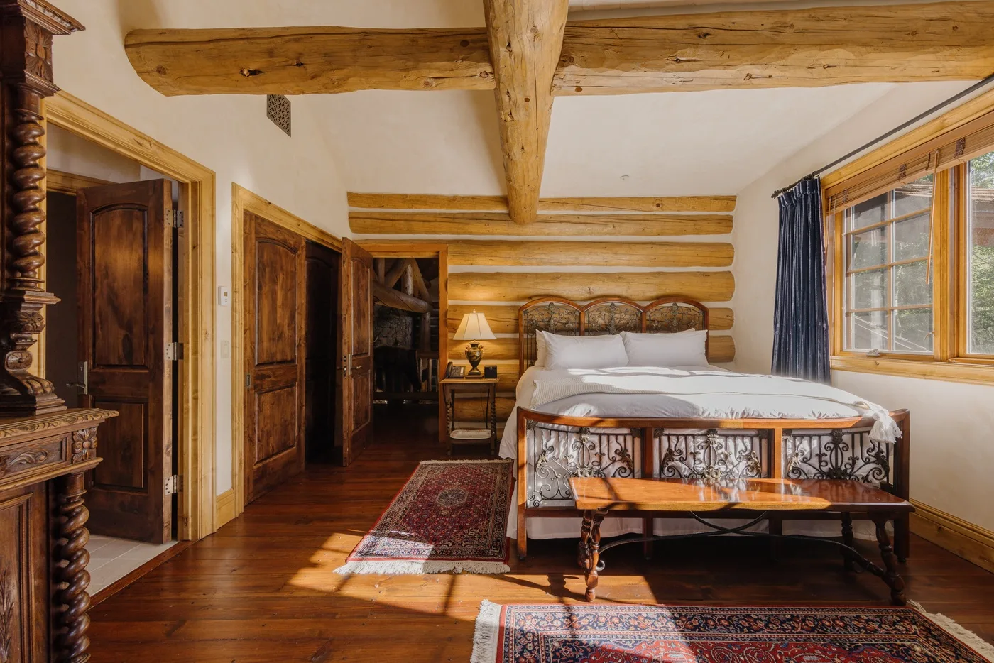 Un dormitorio con una cama, vigas de madera a la vista y una ventana.
