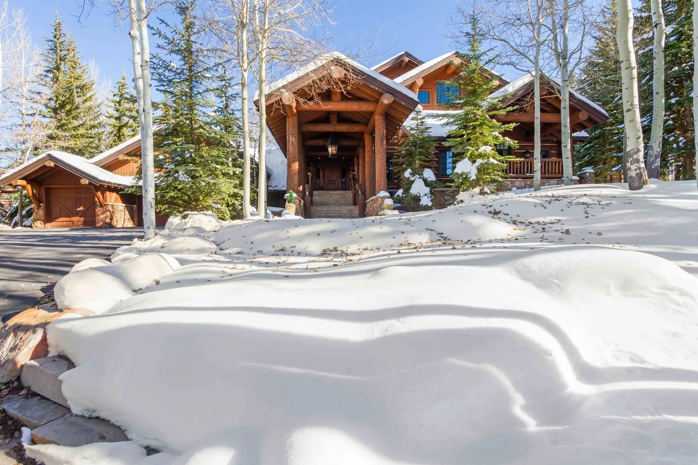 Un albergue de madera se encuentra entre árboles nevados junto a un montículo de nieve.