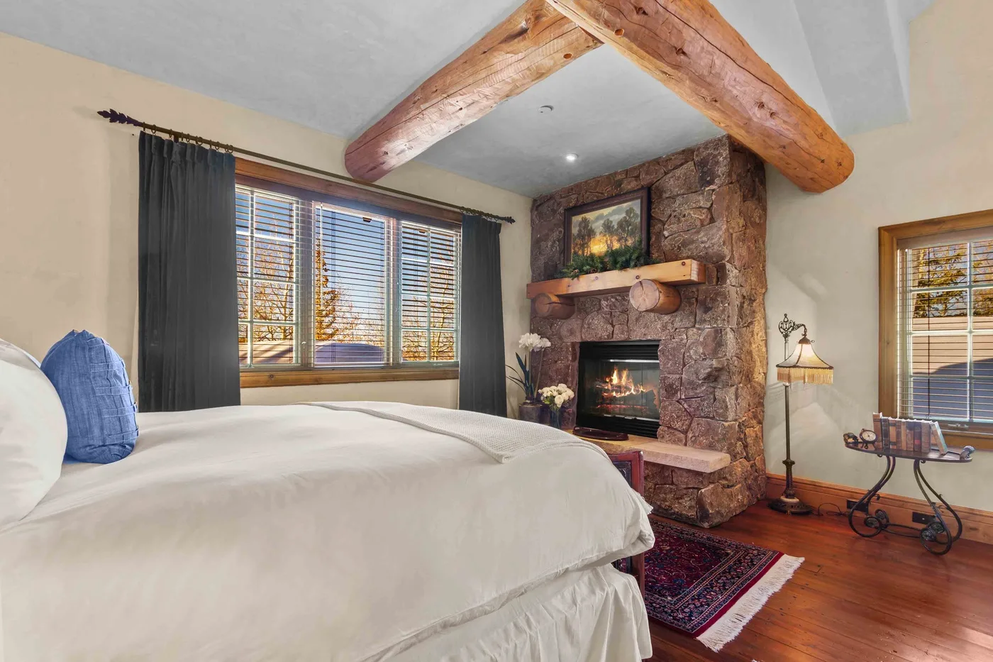 Un dormitorio con una cama, una chimenea de piedra y vigas de madera expuestas.