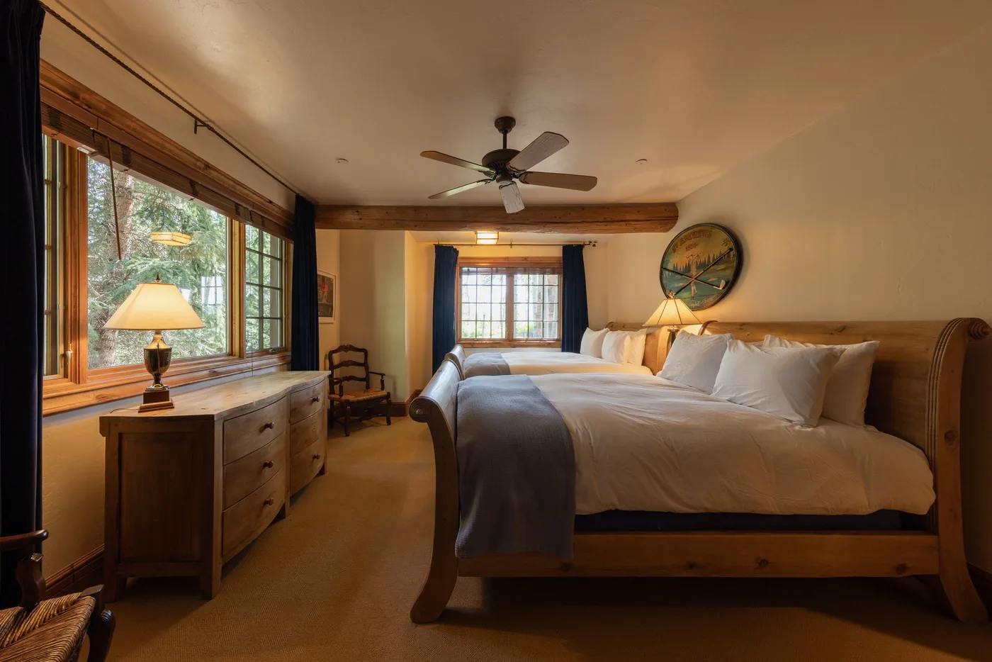 Un dormitorio con una cama de madera, ropa de cama blanca y ventanas a un lado.