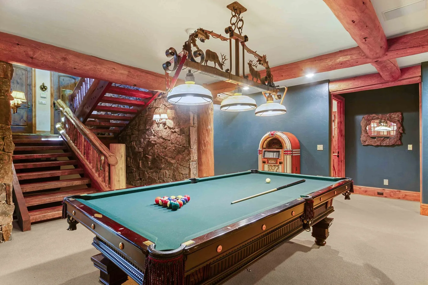 Una sala de billar con una mesa verde y una escalera junto a la pared.