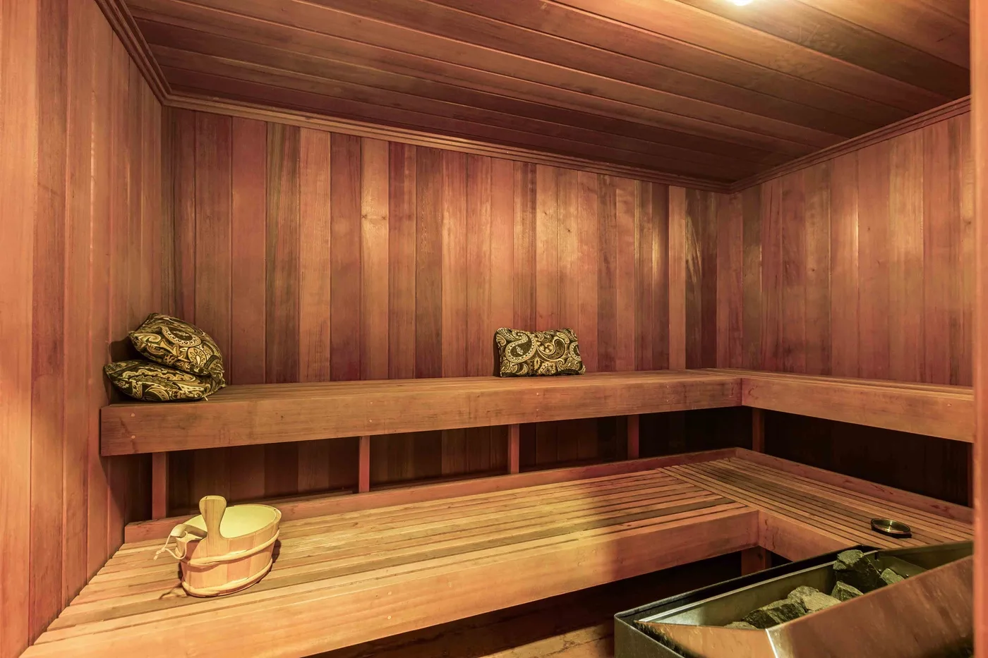 Una sauna revestida de madera con bancos escalonados y toallas dobladas.