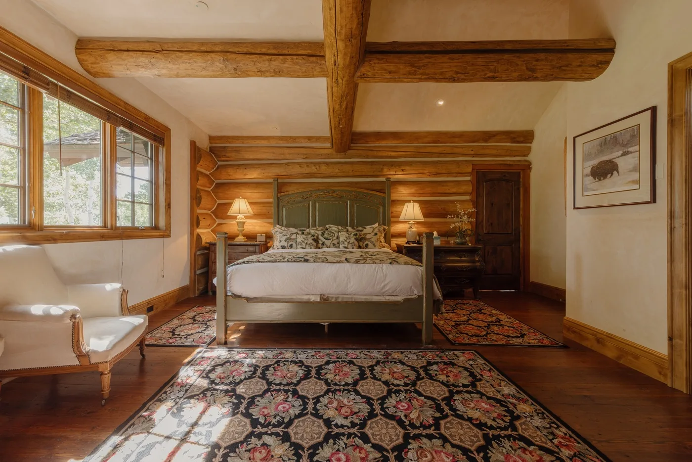 Dormitorio con una cama, alfombras estampadas y vigas de madera a la vista.