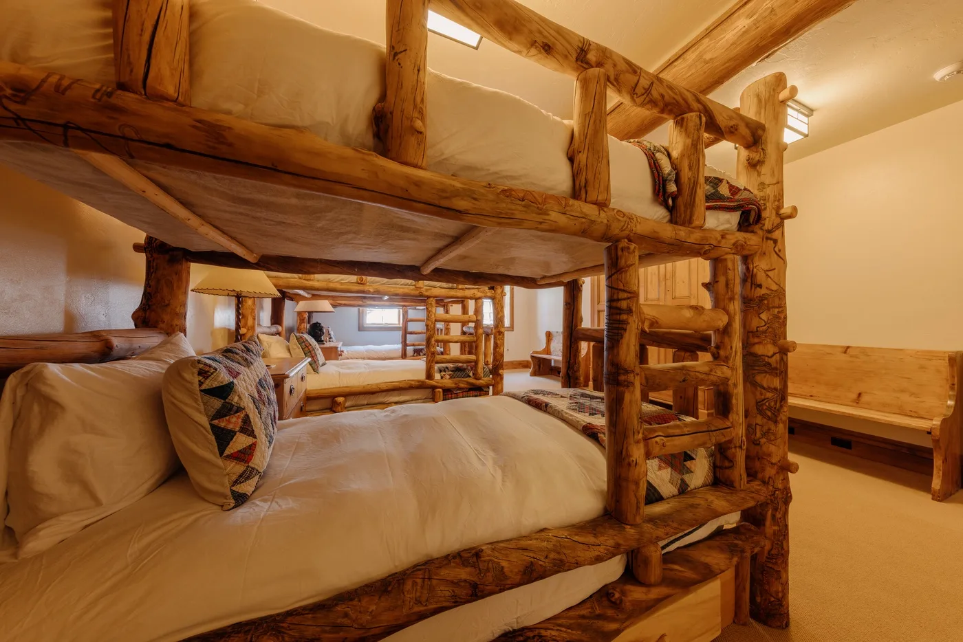 Un dormitorio rústico con literas de madera y la cama inferior bien arreglada.