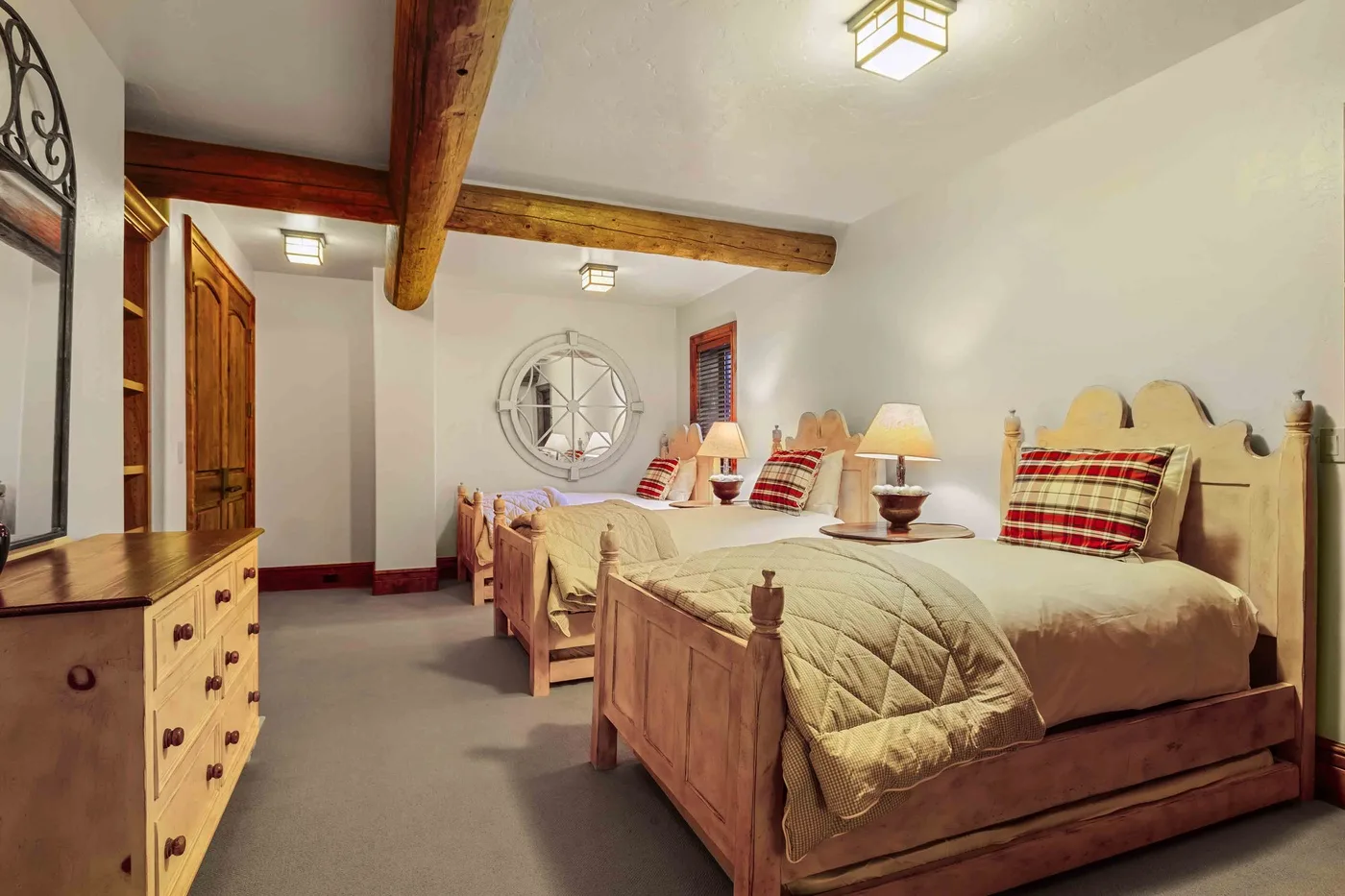 Un dormitorio con camas de madera, almohadas estampadas y vigas a la vista.