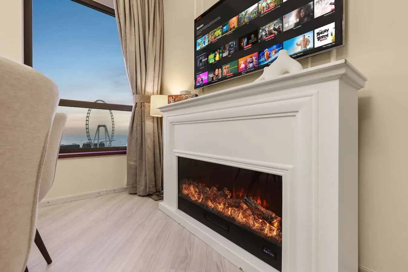 A living room features a television above a fireplace beside a window.