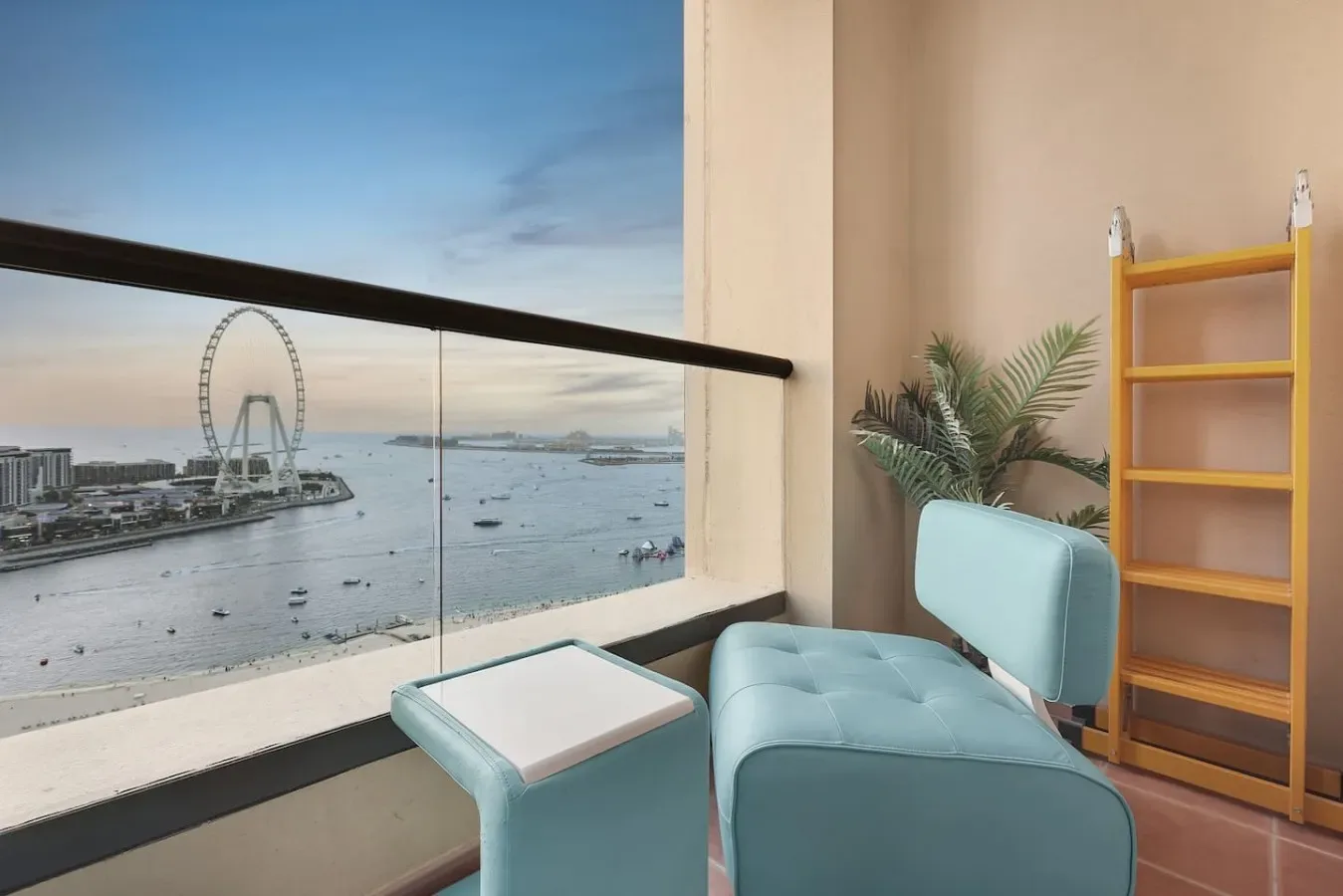 A seating area beside a large window overlooks a waterfront and a Ferris wheel.