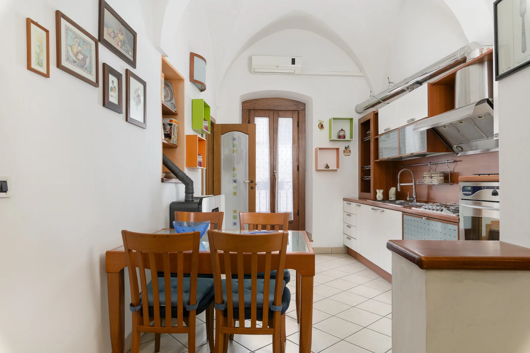 Una cocina luminosa con comedor, mesa de madera y cuadros enmarcados.