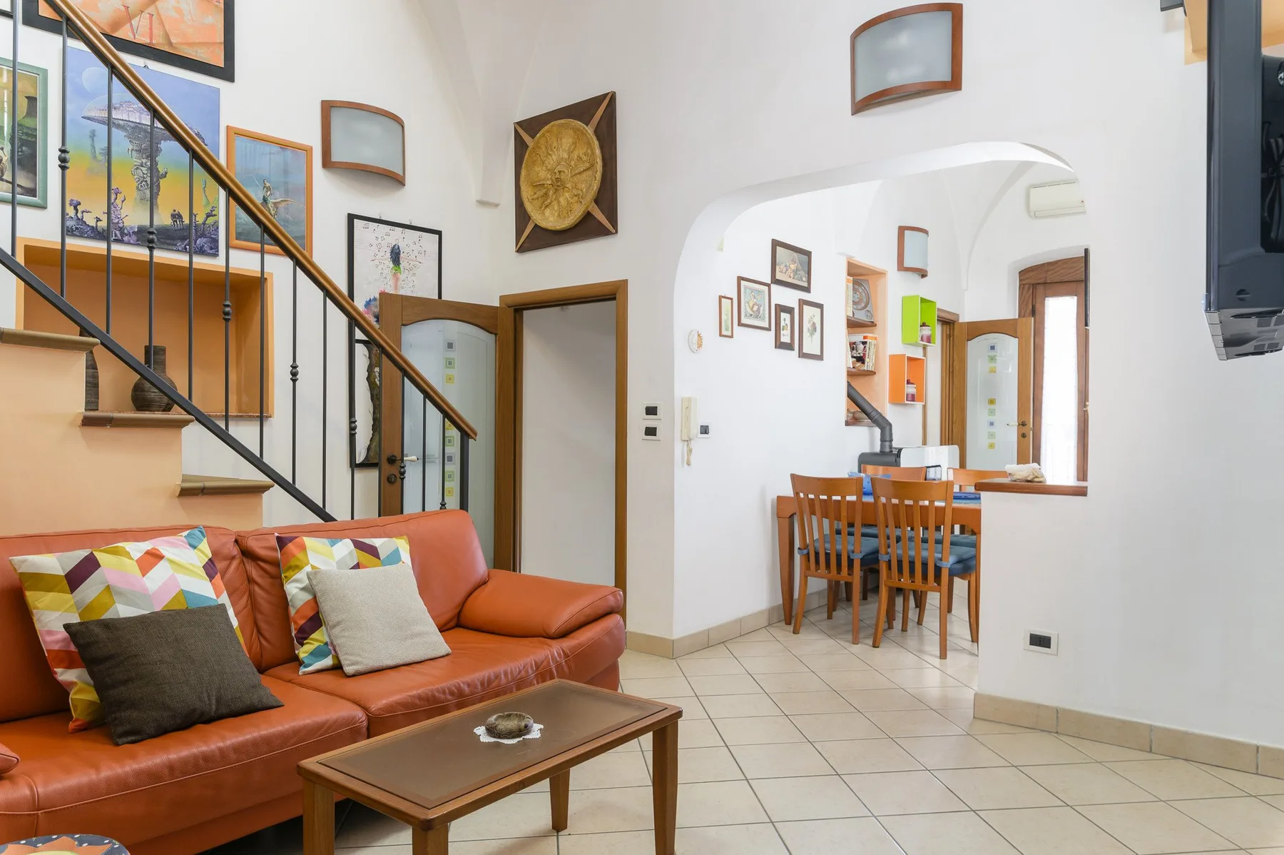 Una sala de estar con una zona para sentarse bajo una escalera y un comedor contiguo.