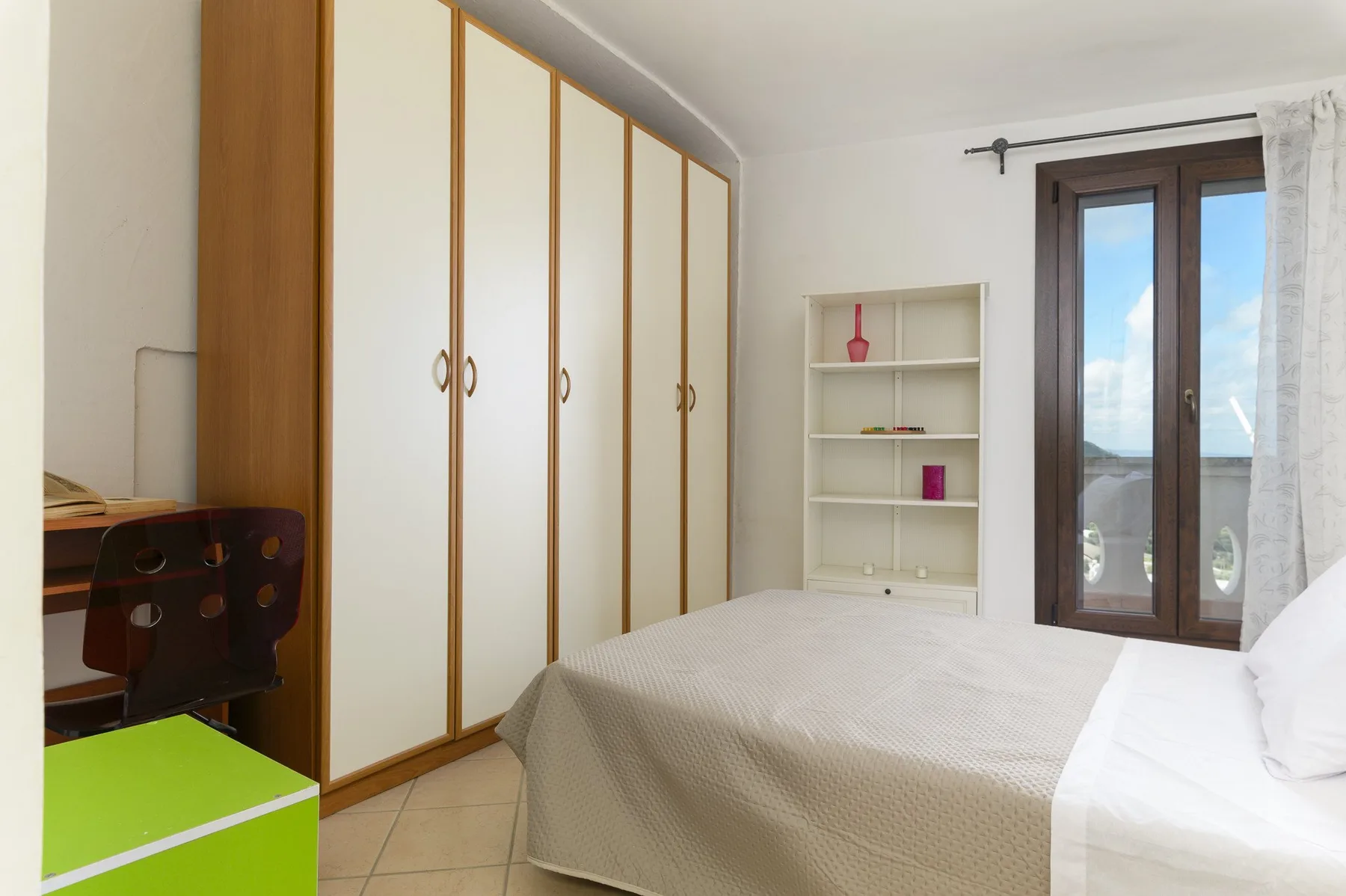 Un dormitorio con una cama, armarios empotrados y una ventana con vistas al agua.
