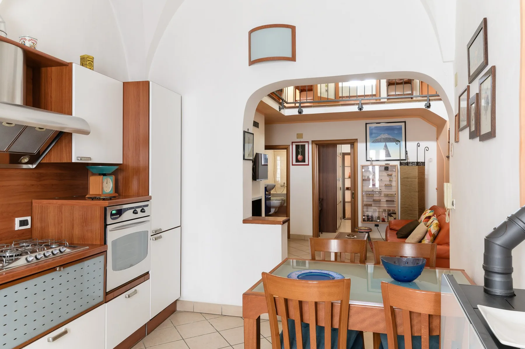 Una cocina y comedor se abren a través de un arco hacia una sala.