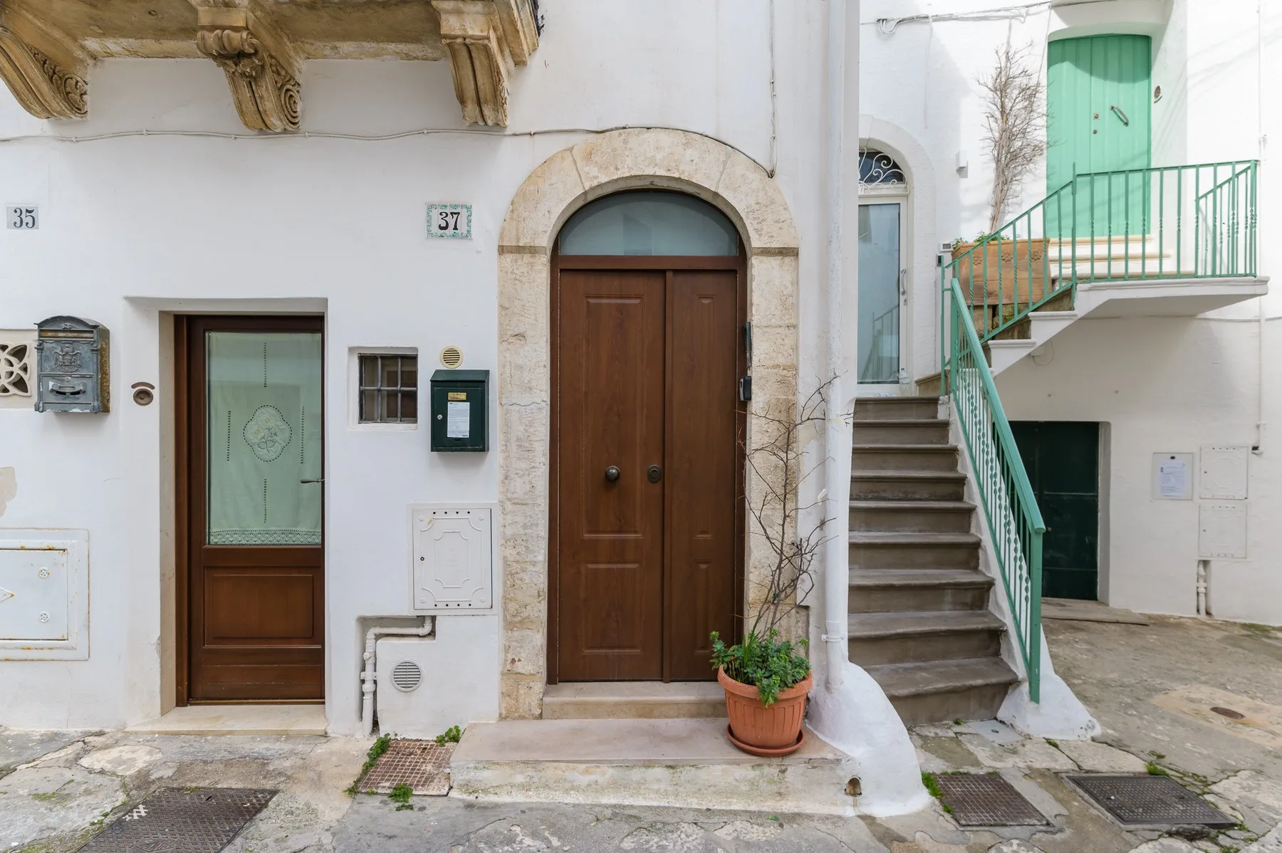 Fachadas blancas con entradas de madera y una escalera exterior.