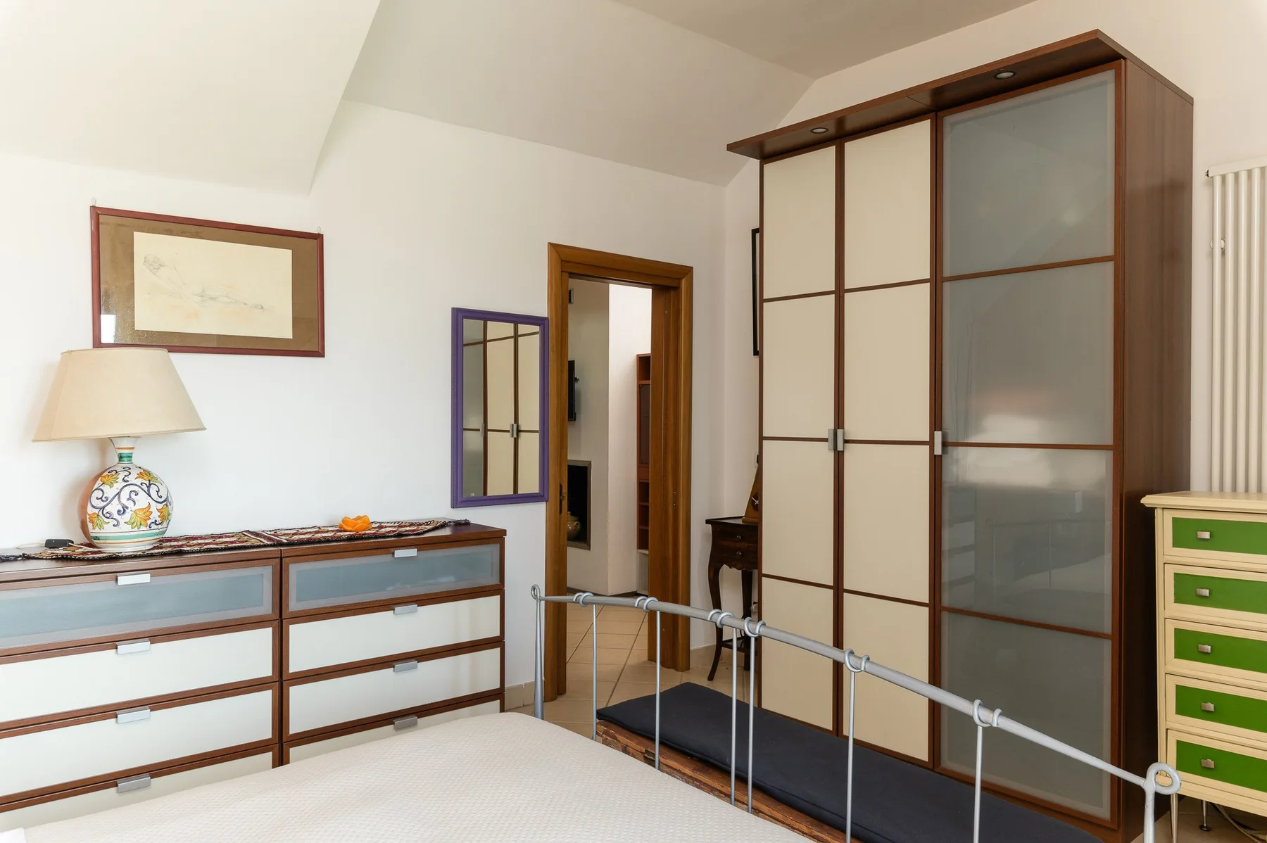 Un dormitorio con una cama, un armario grande y una cómoda baja.