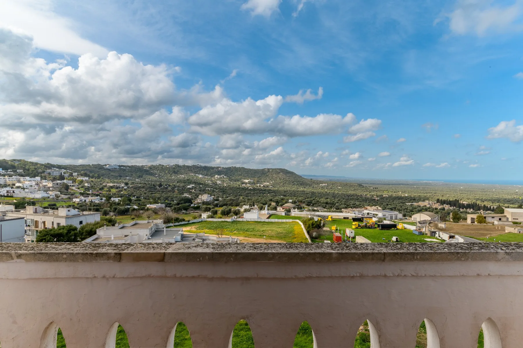 Una vista amplia de un pueblo y campos verdes bajo un cielo azul con nubes.