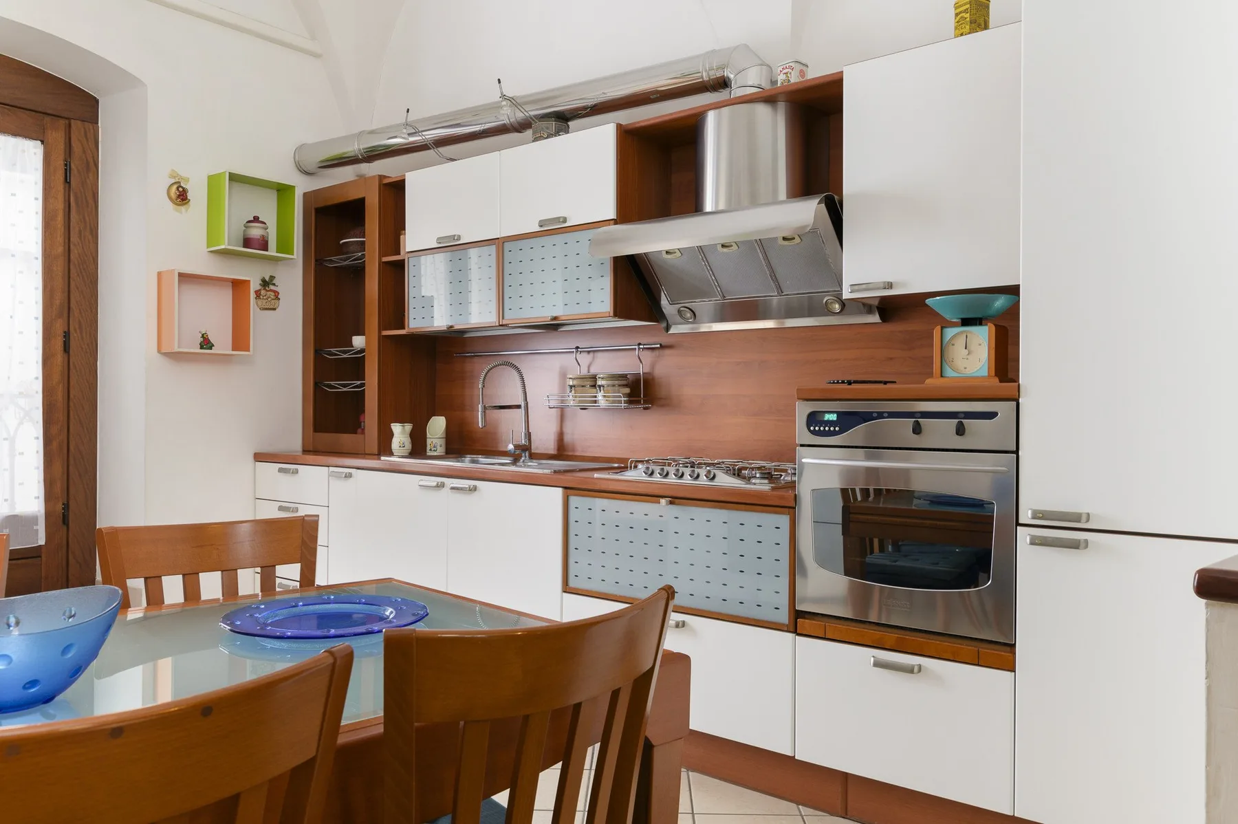 Una cocina y comedor con sillas de madera y electrodomésticos integrados.